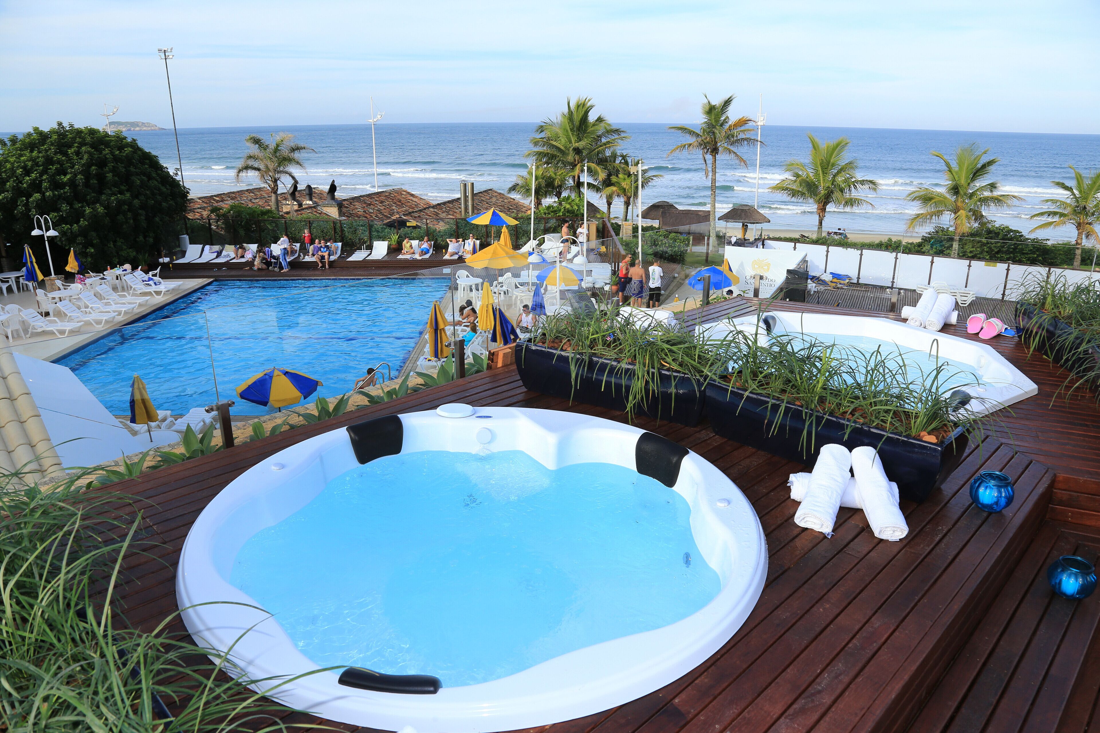 Un área de piscina con jacuzzi, sillas de descanso y sombrillas.