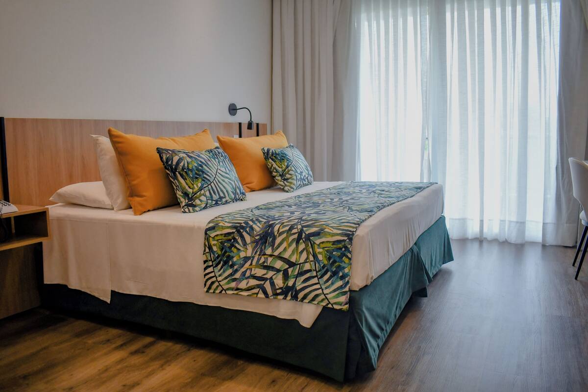 A hotel room with a bed, a nightstand, a desk, and a chair.