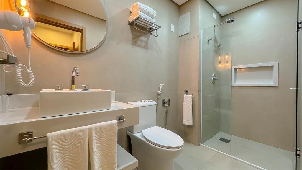 A modern bathroom with a sink, toilet, and glass shower enclosure.