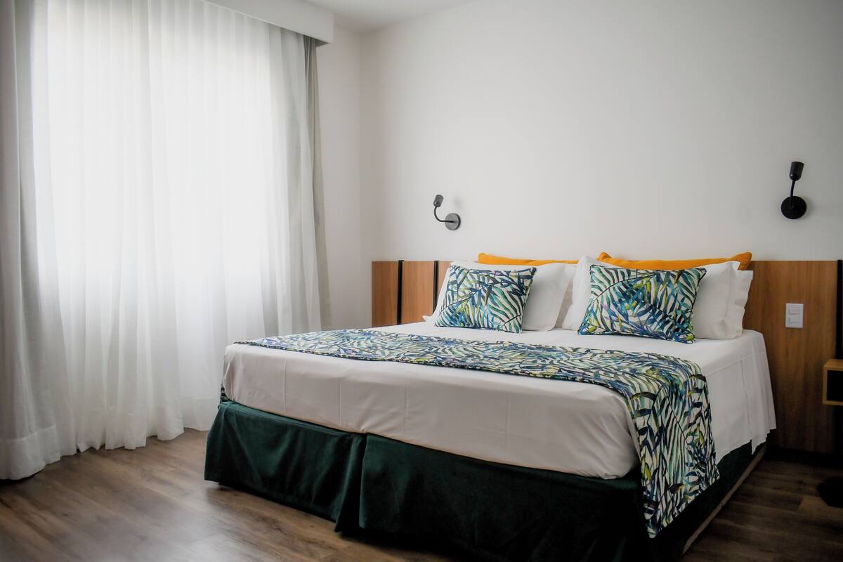A neatly made bed with a patterned bedspread, a wooden headboard, and a bedside table with a lamp.