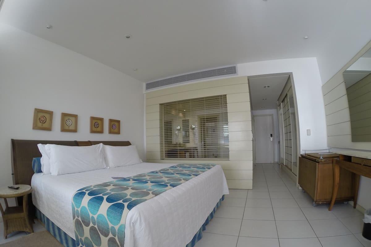 A hotel room with a bed, bedside table, and a desk with a mirror.