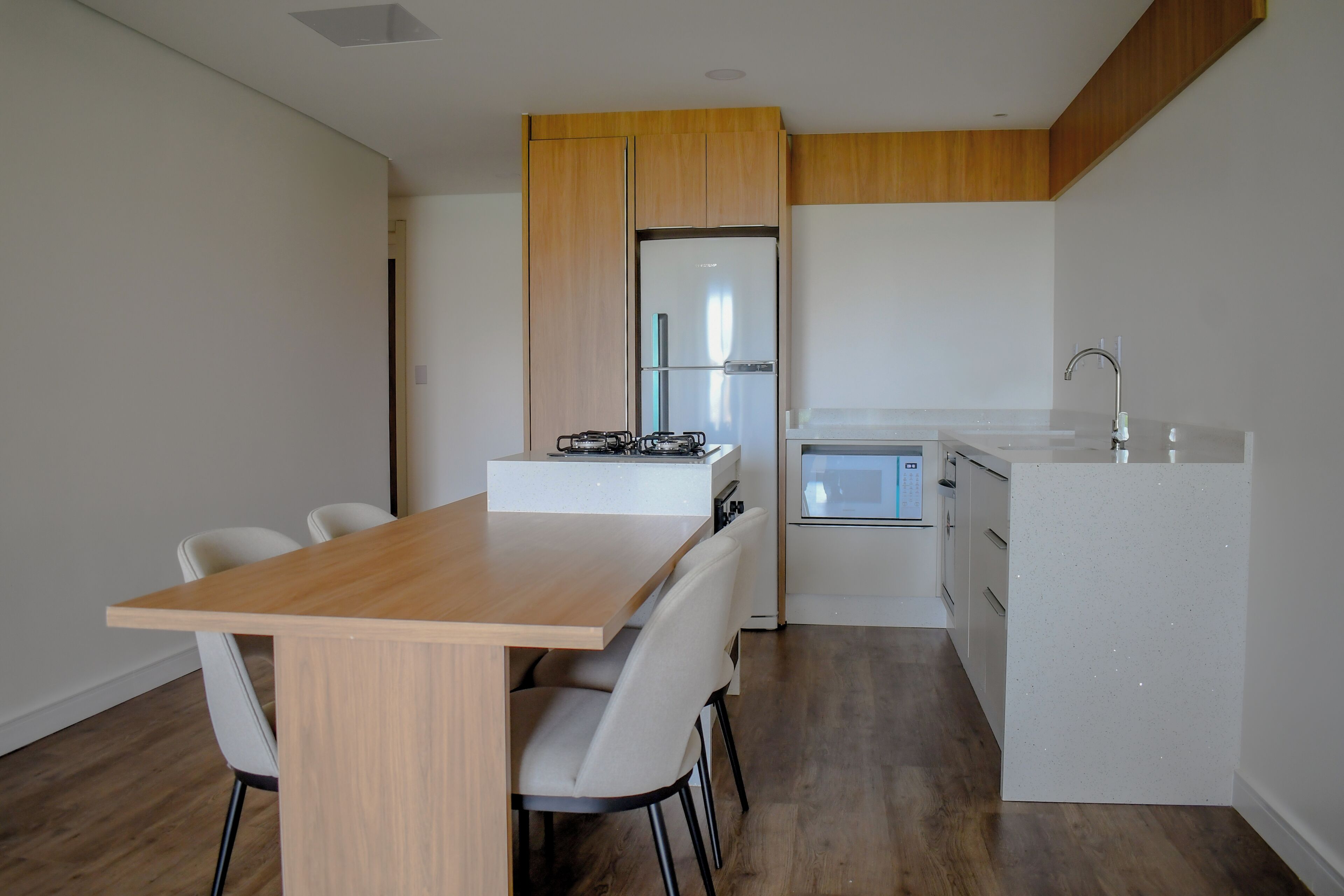 Una cocina moderna con estufa a gas integrada, muebles blancos y un lavamanos de acero inoxidable.