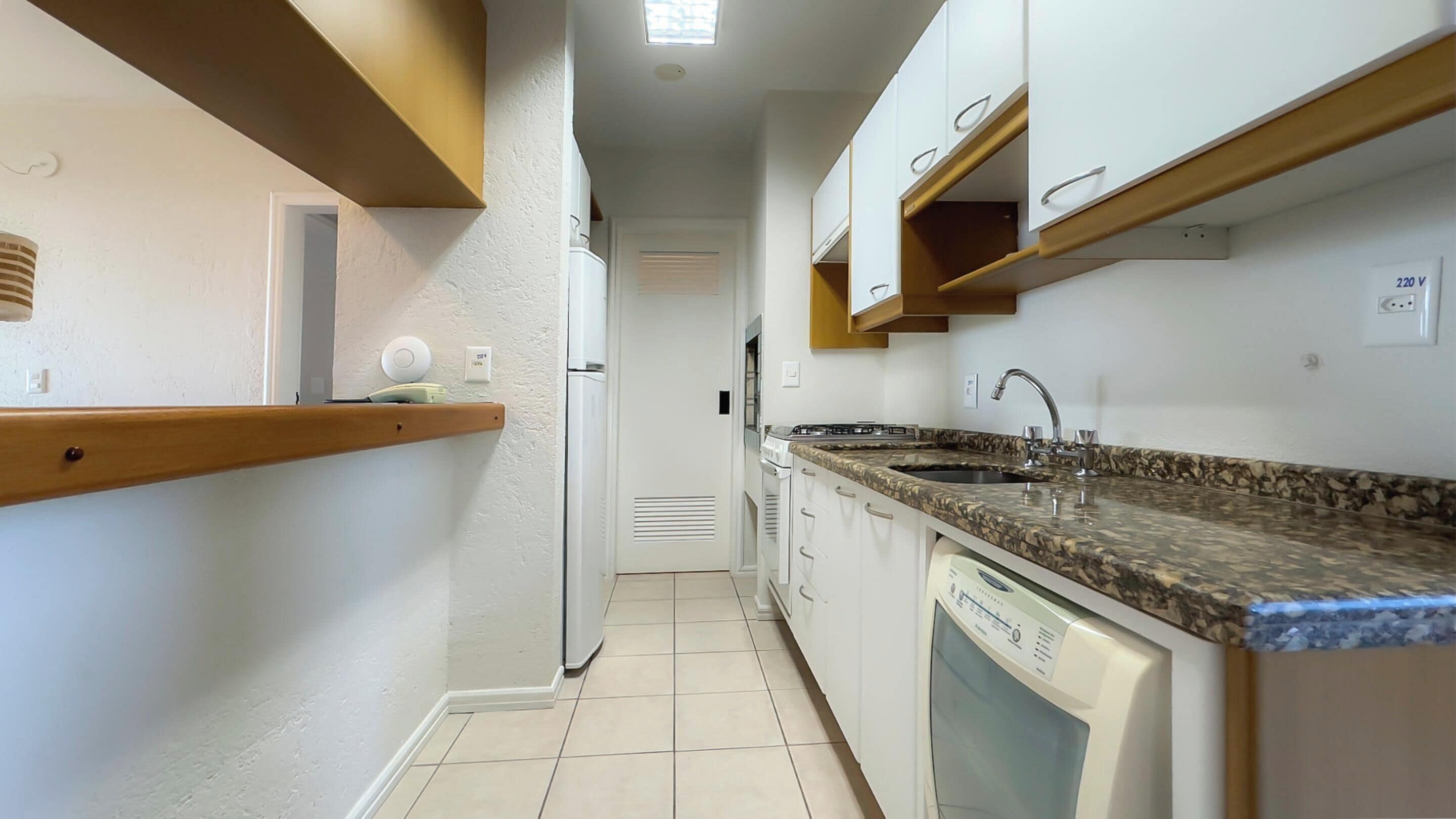 A narrow kitchen with white cabinets, a granite countertop, and a dishwasher.