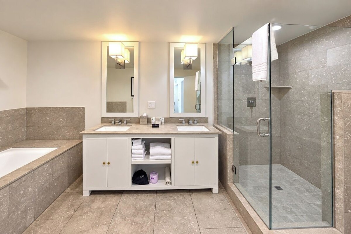 A modern bathroom with two sinks, a glass shower enclosure, and a walk-in shower.
