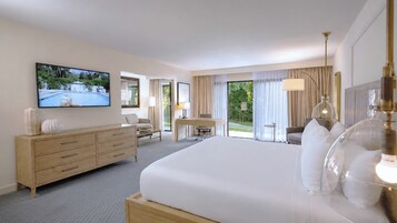 Habitación de hotel con una cama grande, un televisor montado en la pared, un escritorio y vistas al exterior a través de las ventanas.