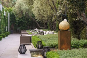 A pathway lined with outdoor furniture and decorative lanterns, leading through a lush garden area. - Luxe Sunset Boulevard Hotel (Los Angeles)