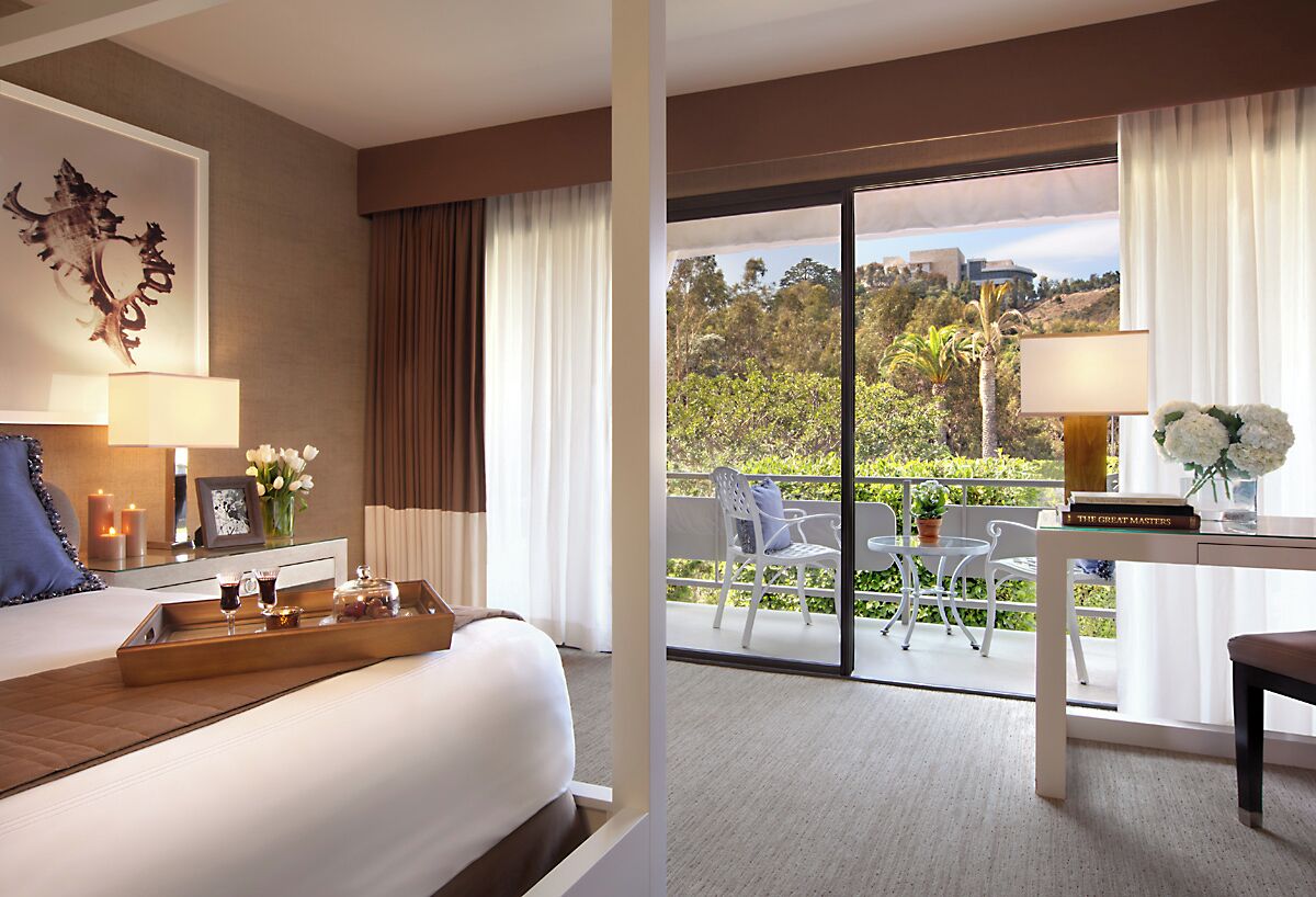 Une chambre d’hôtel avec un lit, une table de chevet avec une lampe, un plateau avec des verres et une vue sur l’extérieur grâce à une porte coulissante.