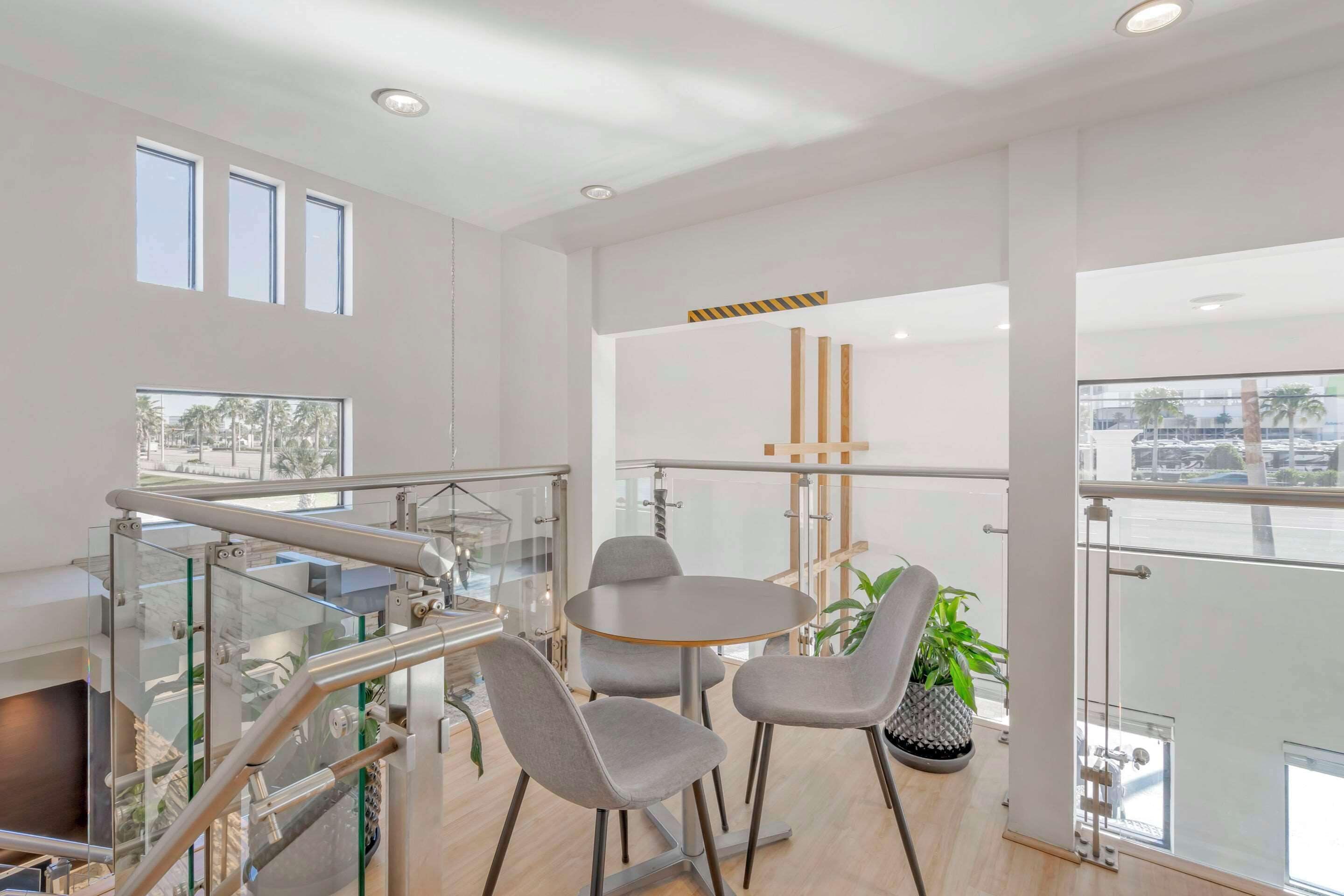 Una habitación de hotel moderna con balcón, una mesa de comedor redonda y dos sillas grises.