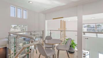 Una habitación de hotel moderna con balcón, una mesa de comedor redonda y dos sillas grises.