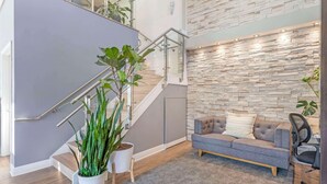 A modern interior with a staircase, grey walls, a grey sofa, and a stone wall. - Quality Inn Daytona Speedway I-95 (Daytona Beach)