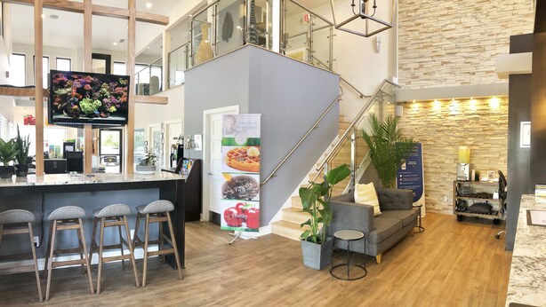 A modern hotel lobby with a bar area, a staircase, and a seating area. - Quality Inn Daytona Speedway I-95 (Daytona Beach)