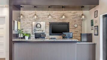 Una reception con una insegna 'Quality', una sveglia e un quadro appeso al muro.
