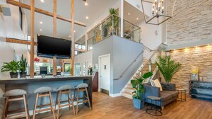 A modern kitchen with a central island, bar stools, and a staircase leading to an upper level. - Quality Inn Daytona Speedway I-95 (Daytona Beach)