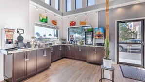 A modern kitchen with dark wood cabinets, a coffee machine, and a fruit display. - Quality Inn Daytona Speedway I-95 (Daytona Beach)