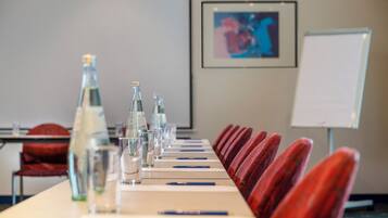 A conference room with a long table, chairs, water bottles, glasses, and a whiteboard.