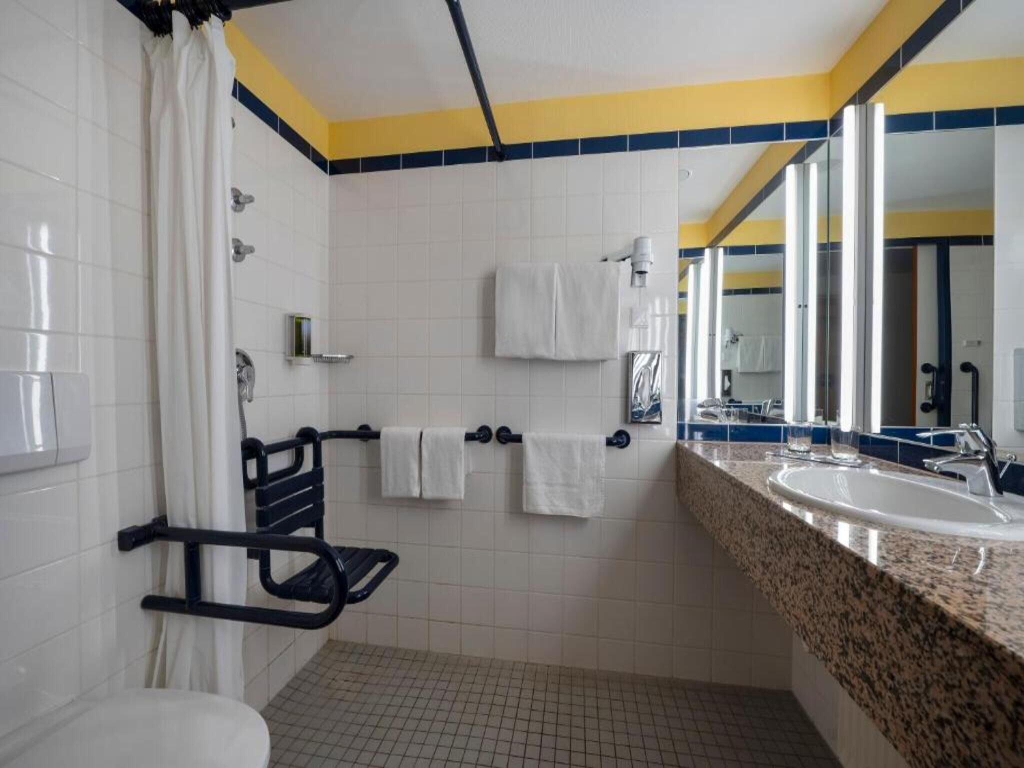 Un baño con ducha, inodoro, lavamanos y espejo.