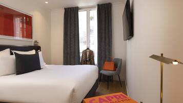 A hotel room with a large bed, a chair, a desk, a television, and a window with curtains.