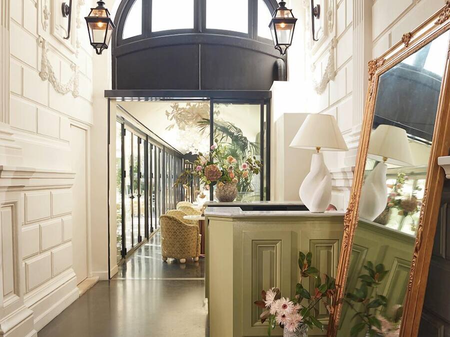 A hallway with a green accent wall, a large mirror, and a lamp.
