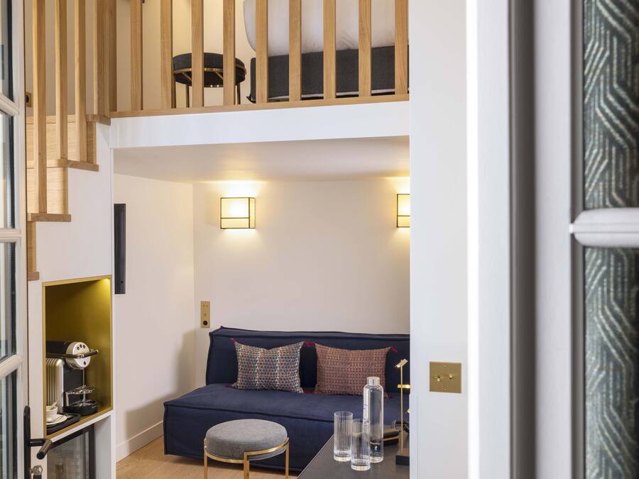 A modern living room with a dark blue sofa, a small round table, and two wall-mounted lamps.