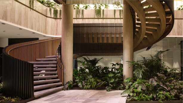 A modern interior with a curved staircase, wooden paneling, and lush indoor plants. - Orea Congress hotel Brno (Brno)
