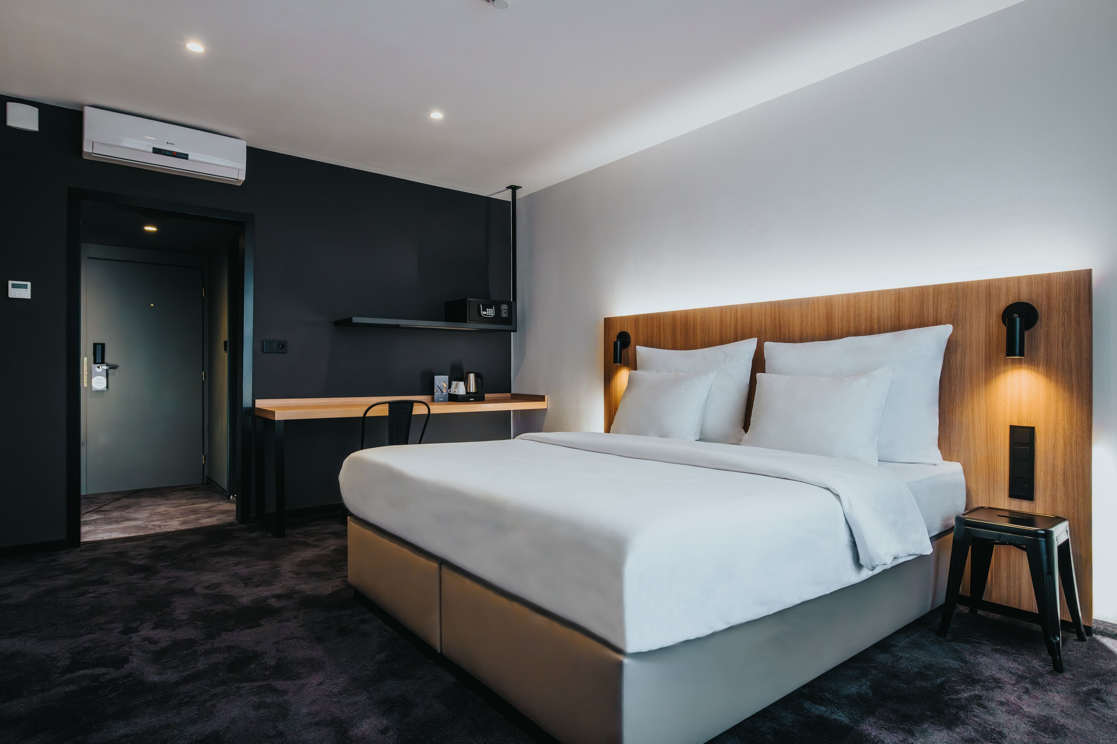 Una habitación de hotel moderna con una cama grande, un escritorio y un estante empotrado.