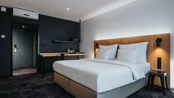 Una habitación de hotel moderna con una cama grande, un escritorio y un estante empotrado.