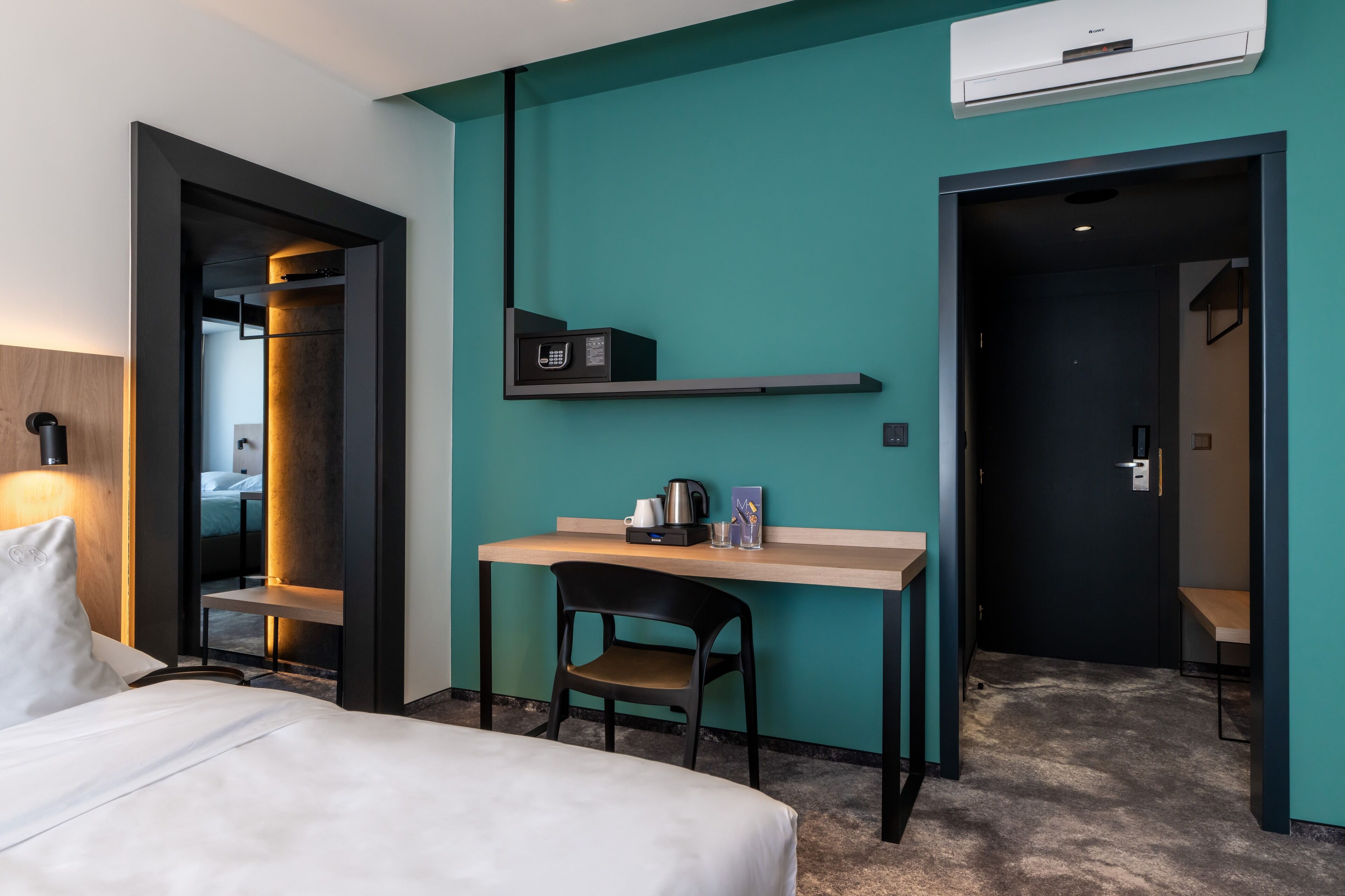 Habitación de hotel con cama, escritorio con silla, microondas y cafetera.