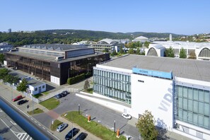A modern building with a large glass facade, a sign reading "VIDA", and a parking lot with several cars.