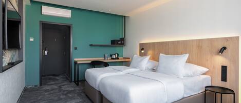 Una habitación de hotel moderna con una cama grande, un escritorio, una silla y una pequeña mesa.