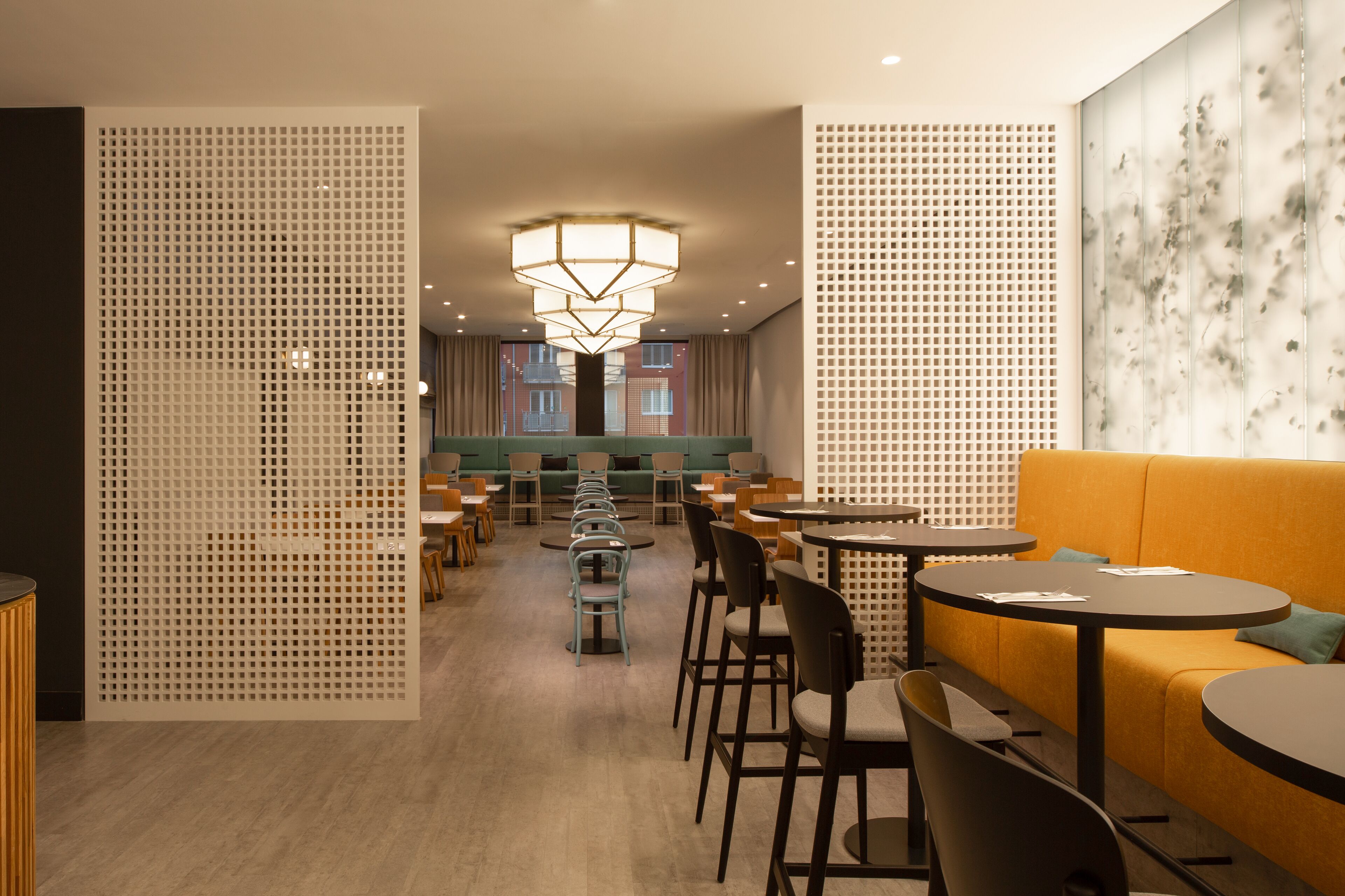 Un interior moderno con una zona de estar central, mesas y sillas dispuestas para comer o conversar.