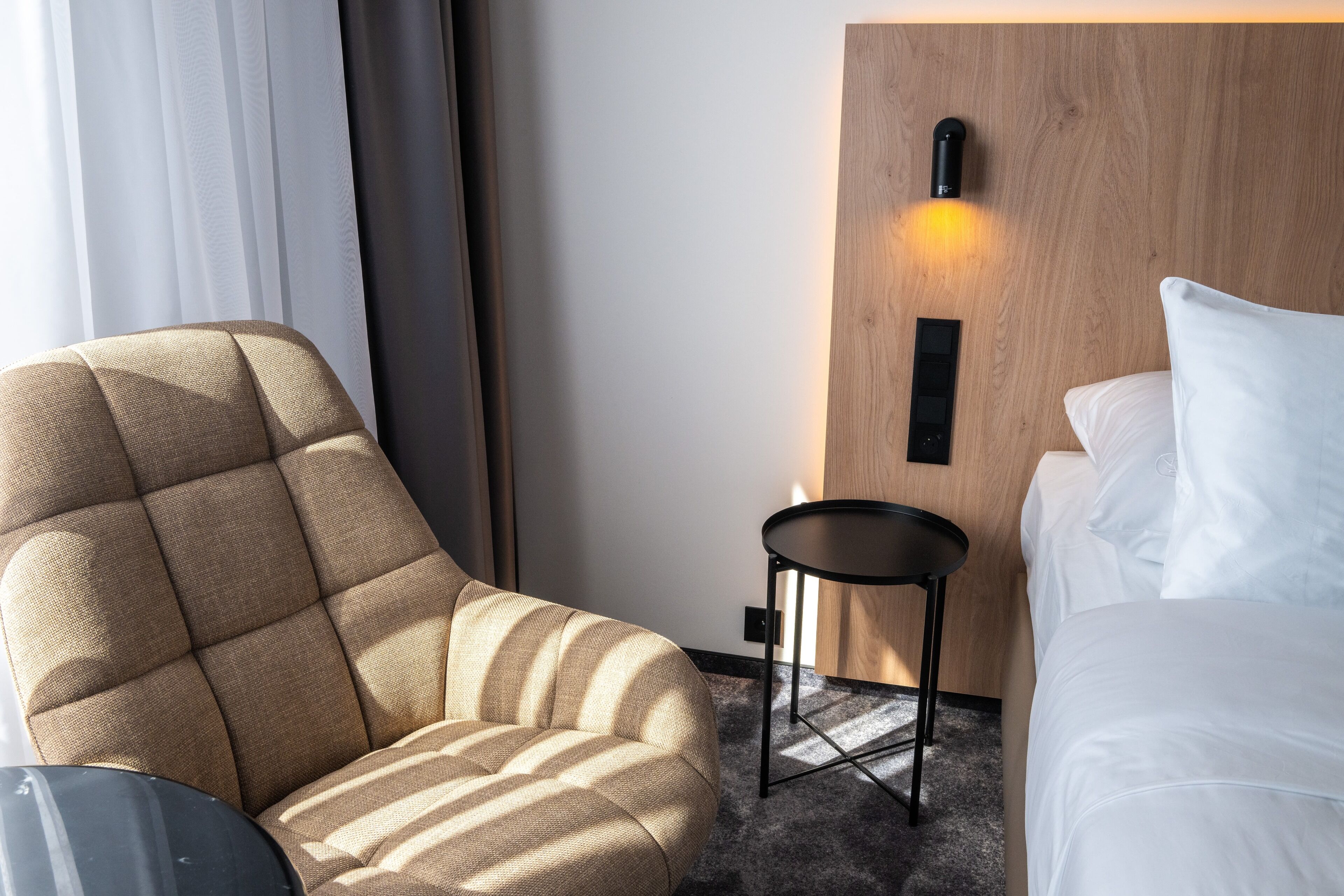 Ein Hotelzimmer mit Bett, Sofa, kleinem Tisch und Wandleuchte.