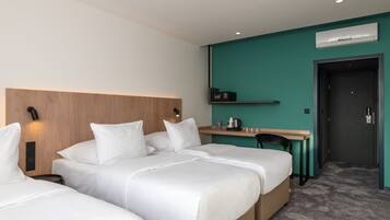 Ein Hotelzimmer mit zwei Betten, einem Schreibtisch, einem Stuhl, einem Nachttisch und einer Wandklimaanlage.