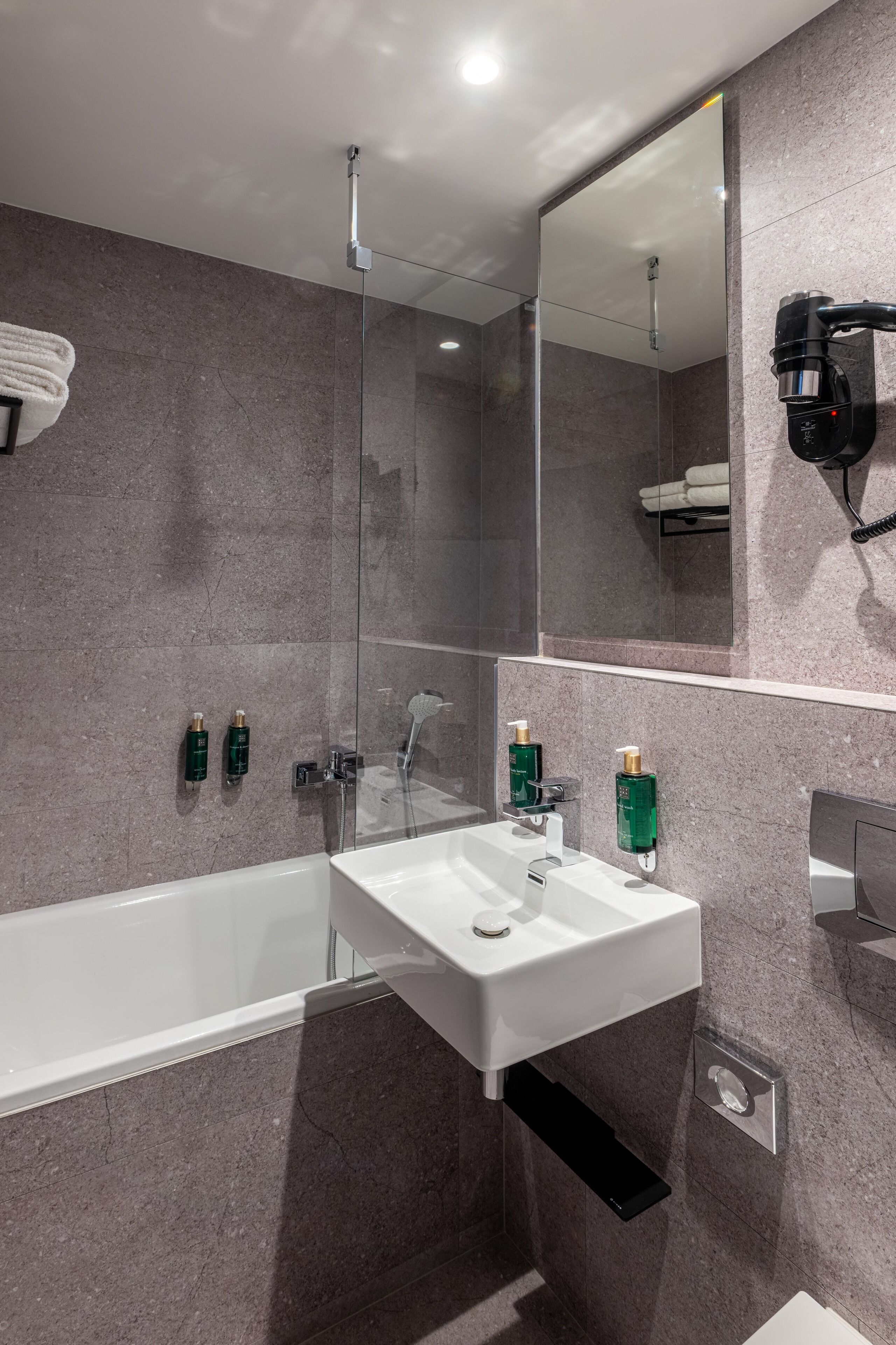 A modern bathroom with a white bathtub, a sink, and a glass-enclosed shower.