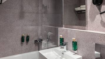 A modern bathroom with a white bathtub, a sink, and a glass-enclosed shower.
