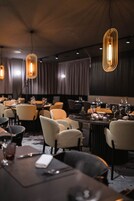 Un restaurante con mesas redondas, sillas y lámparas colgantes.