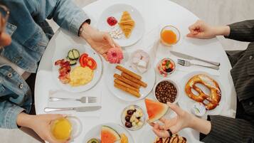 A round table with various breakfast items including croissants, waffles, and fruit.