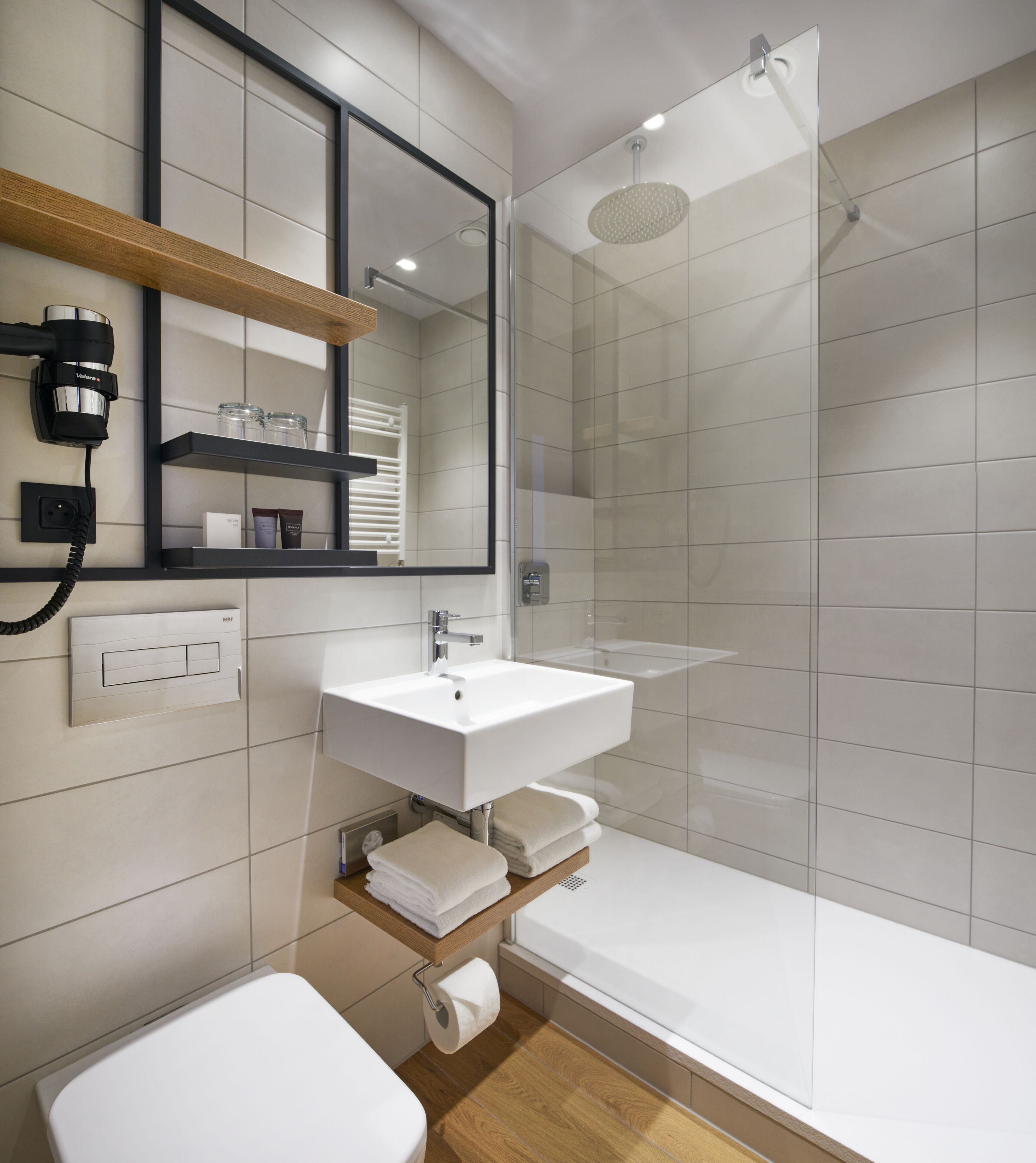 A modern bathroom with a white sink, a mirror, a shower, and a toilet.