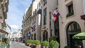 Un hotel con fachada clásica, varias banderas y un toldo verde.