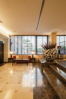 A lobby with a sofa, a coffee table, a decorative vase, and a lamp.