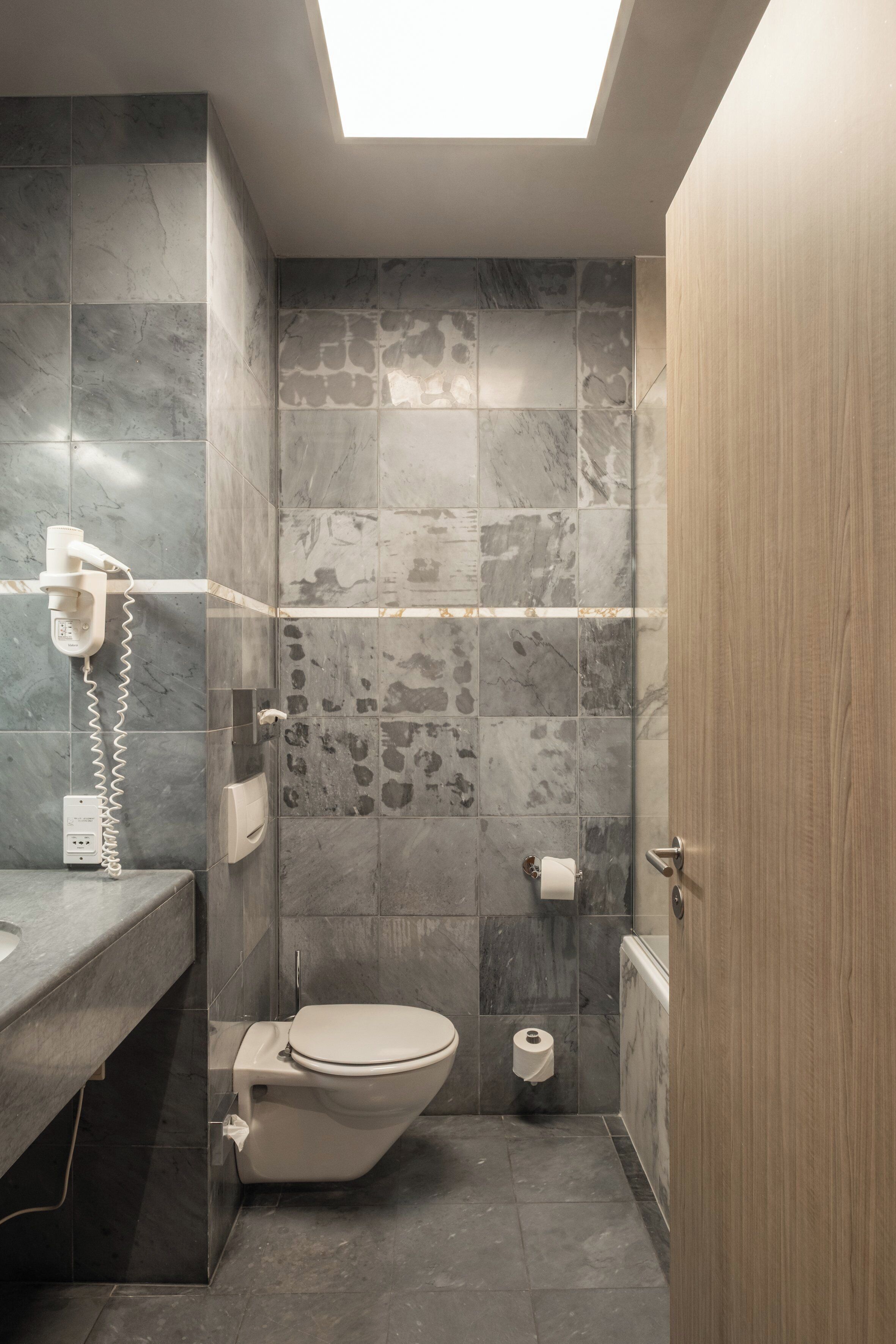 Une salle de bain moderne dotée d’une lucarne, de toilettes, d’un sèche-mains et d’un distributeur de serviettes.