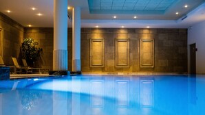 An indoor swimming pool with clear water, a tiled wall with framed panels, and a potted plant. - Hyllit Hotel (Antwerp)