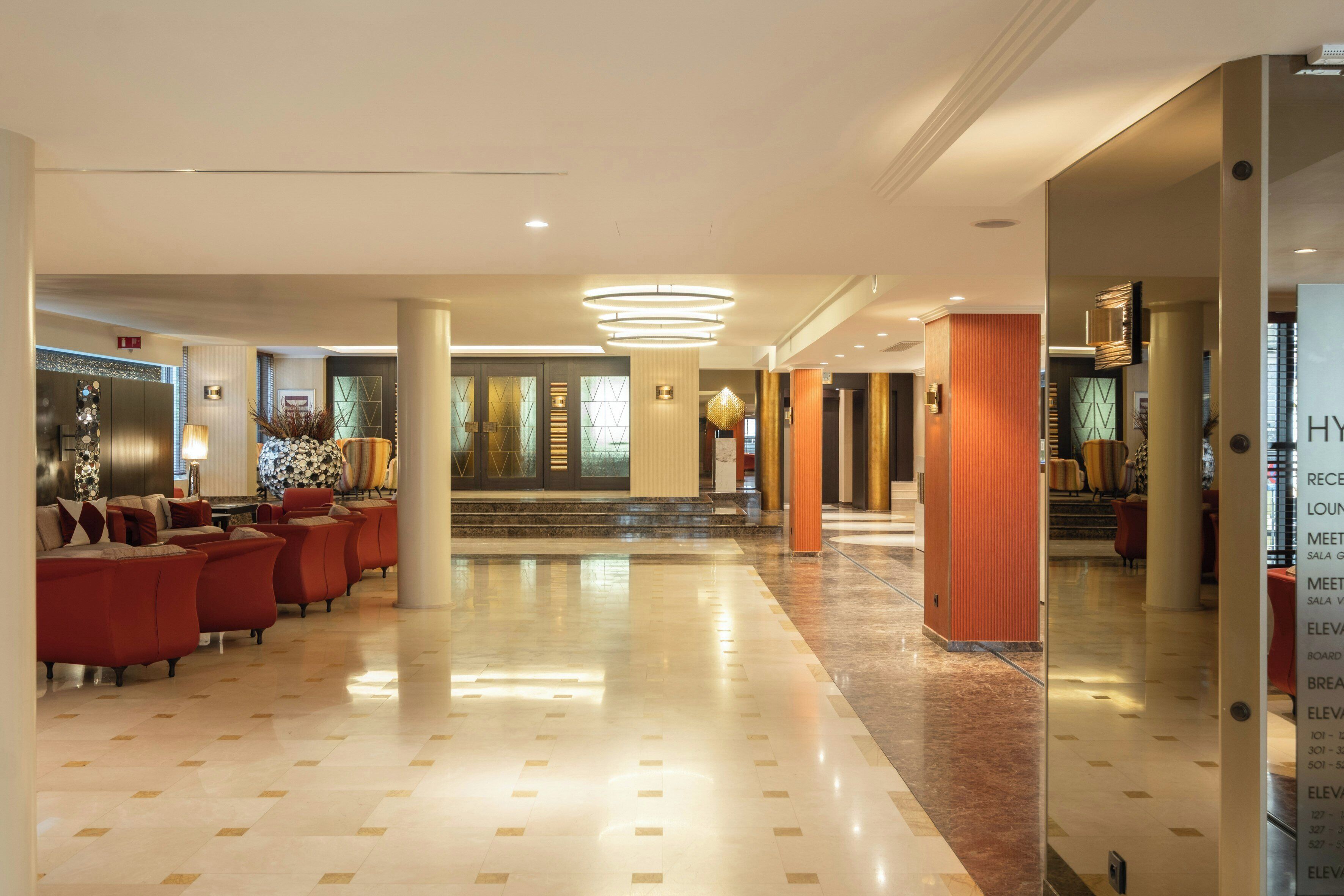 A spacious lobby with a checkered floor, red seating area, and a reception desk.