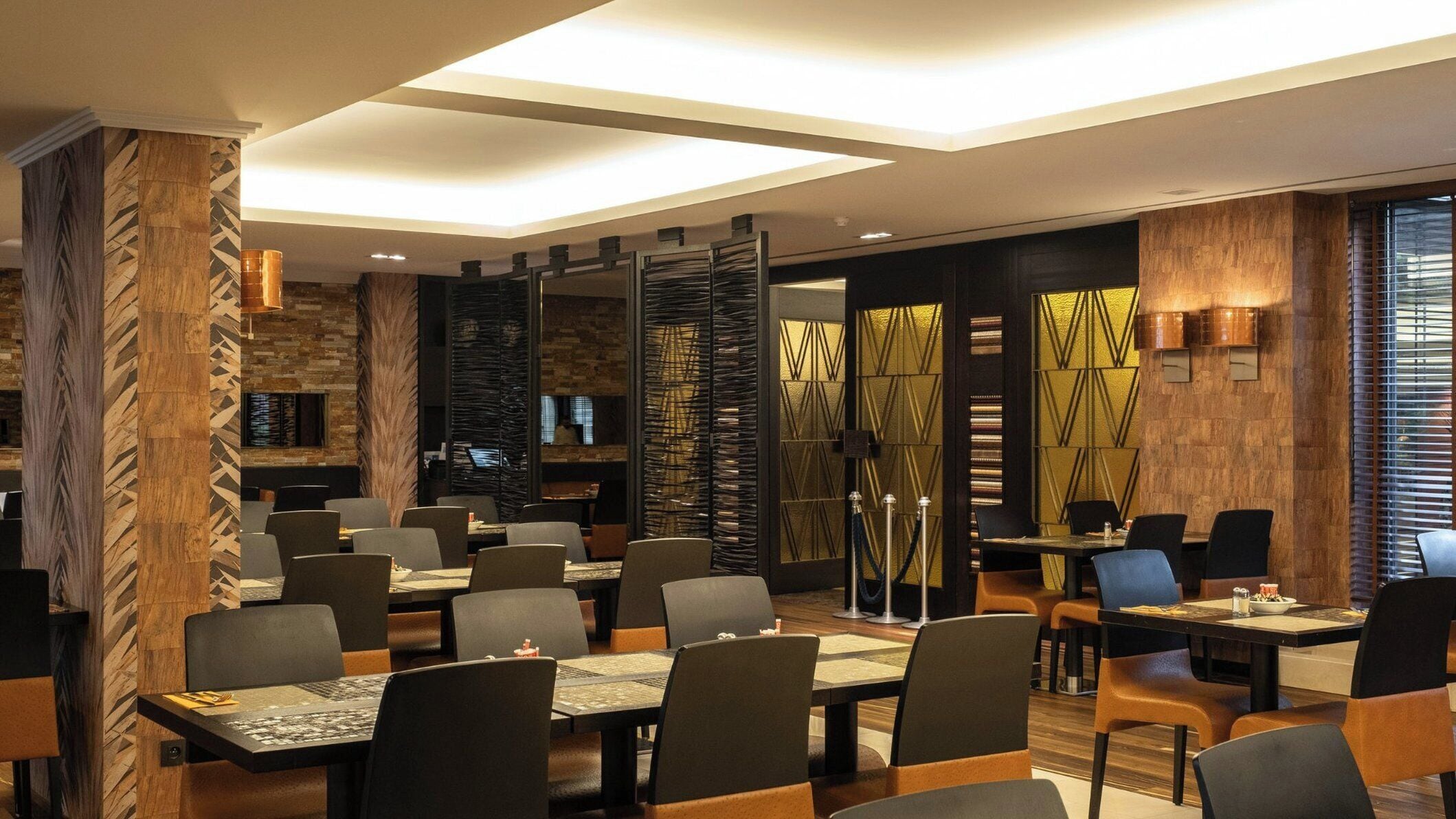 Een modern restaurant met een combinatie van houten en metalen decoratie, met tafels en stoelen voor een diner.