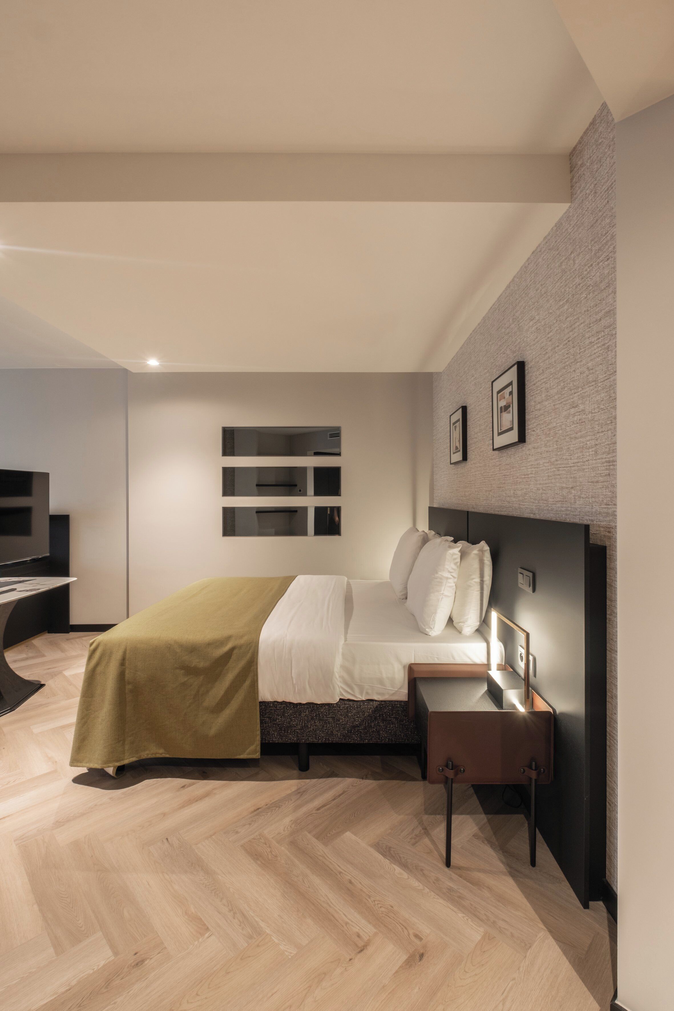 Une chambre moderne avec un lit, une table de chevet et un téléviseur encastré.