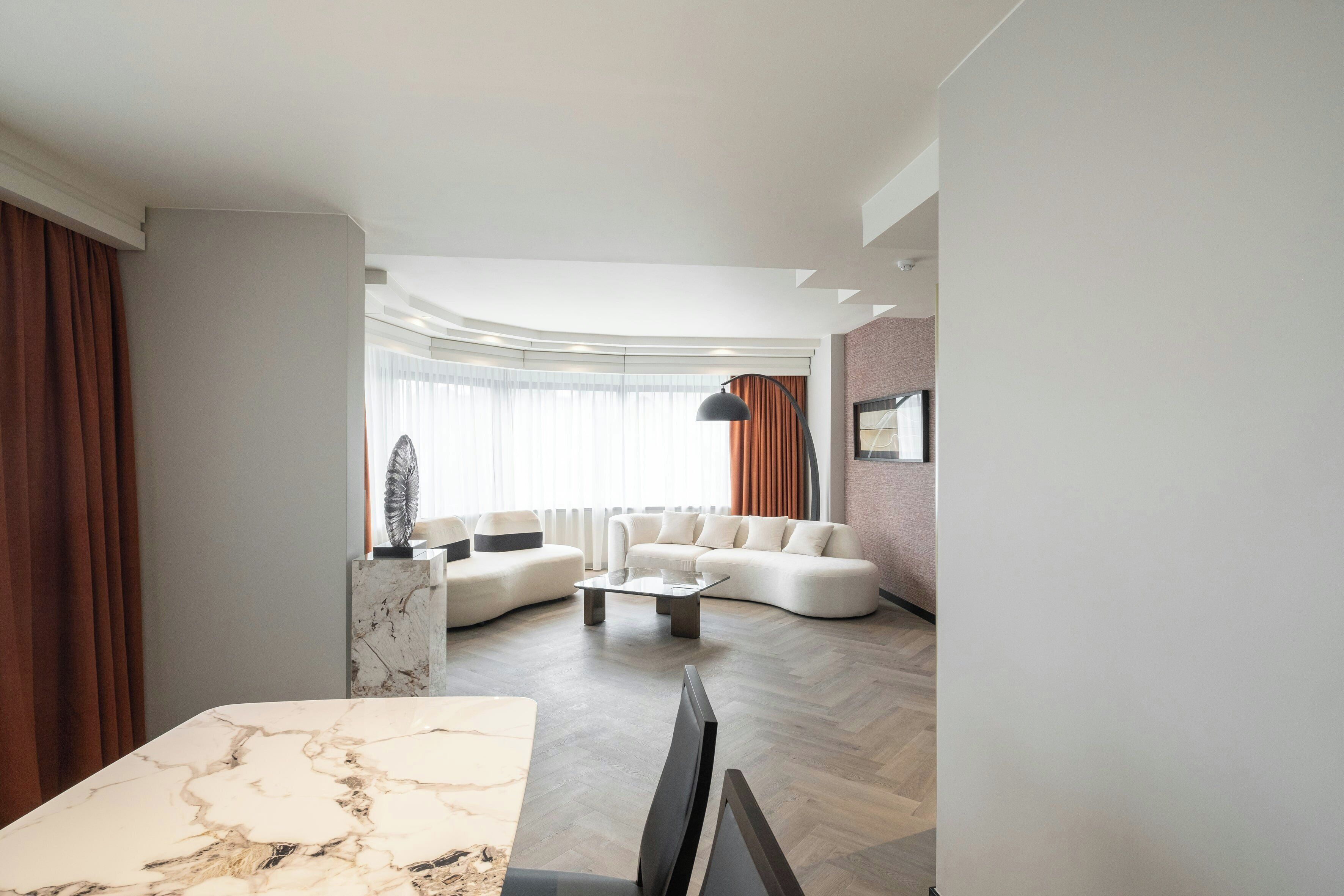 A modern living room with a marble coffee table, a sofa set, and a dining area with a marble table.