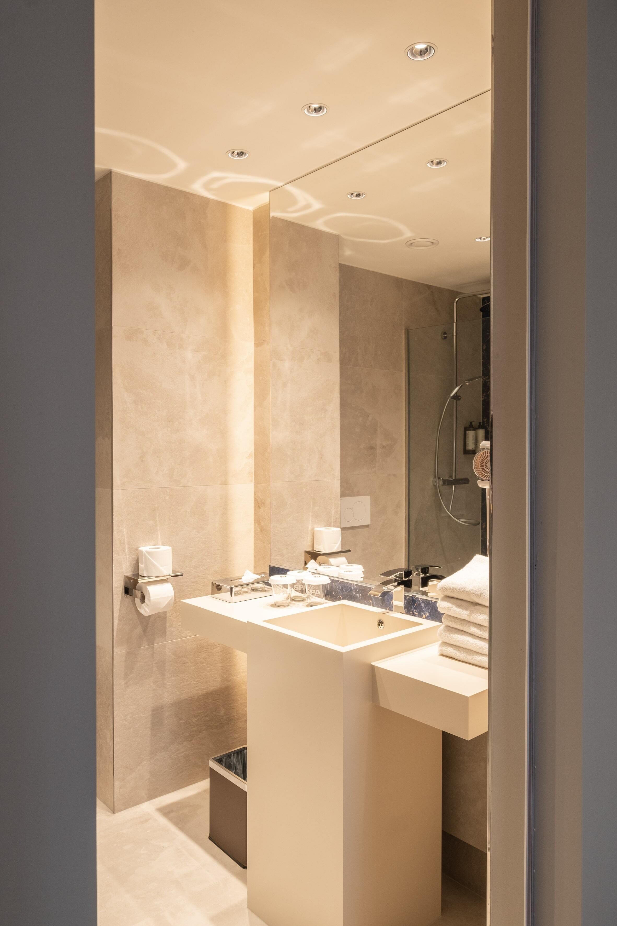 A modern bathroom with a large mirror, a sink, and a shower.