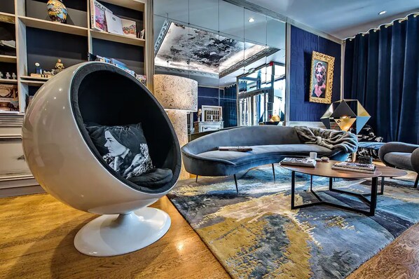 A modern living room with a curved sofa, a unique egg-shaped chair, and a coffee table.