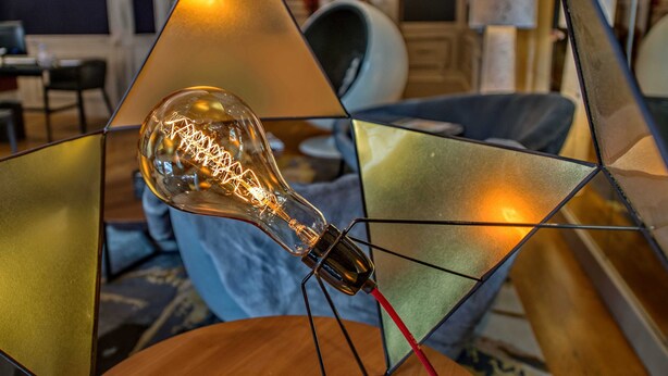 A modern interior with a geometric light fixture and a visible light bulb.