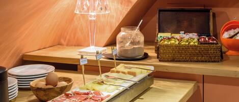 A breakfast buffet with various food items, a lamp, and a basket of fruits.