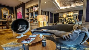 A modern living room with a grey sofa, a round coffee table, a black armchair, and a bookshelf filled with books and decorative items.